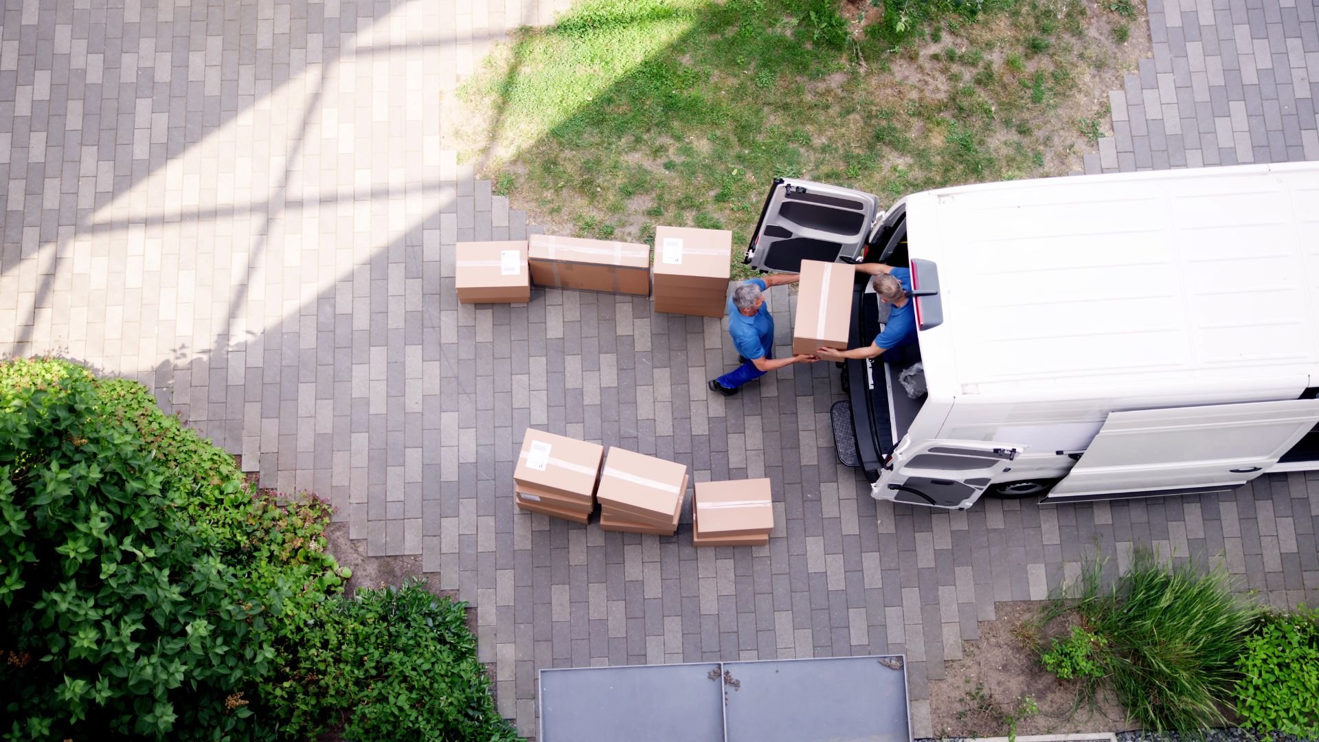 Aerial view of delivery workers unloading cardboard boxes from white van