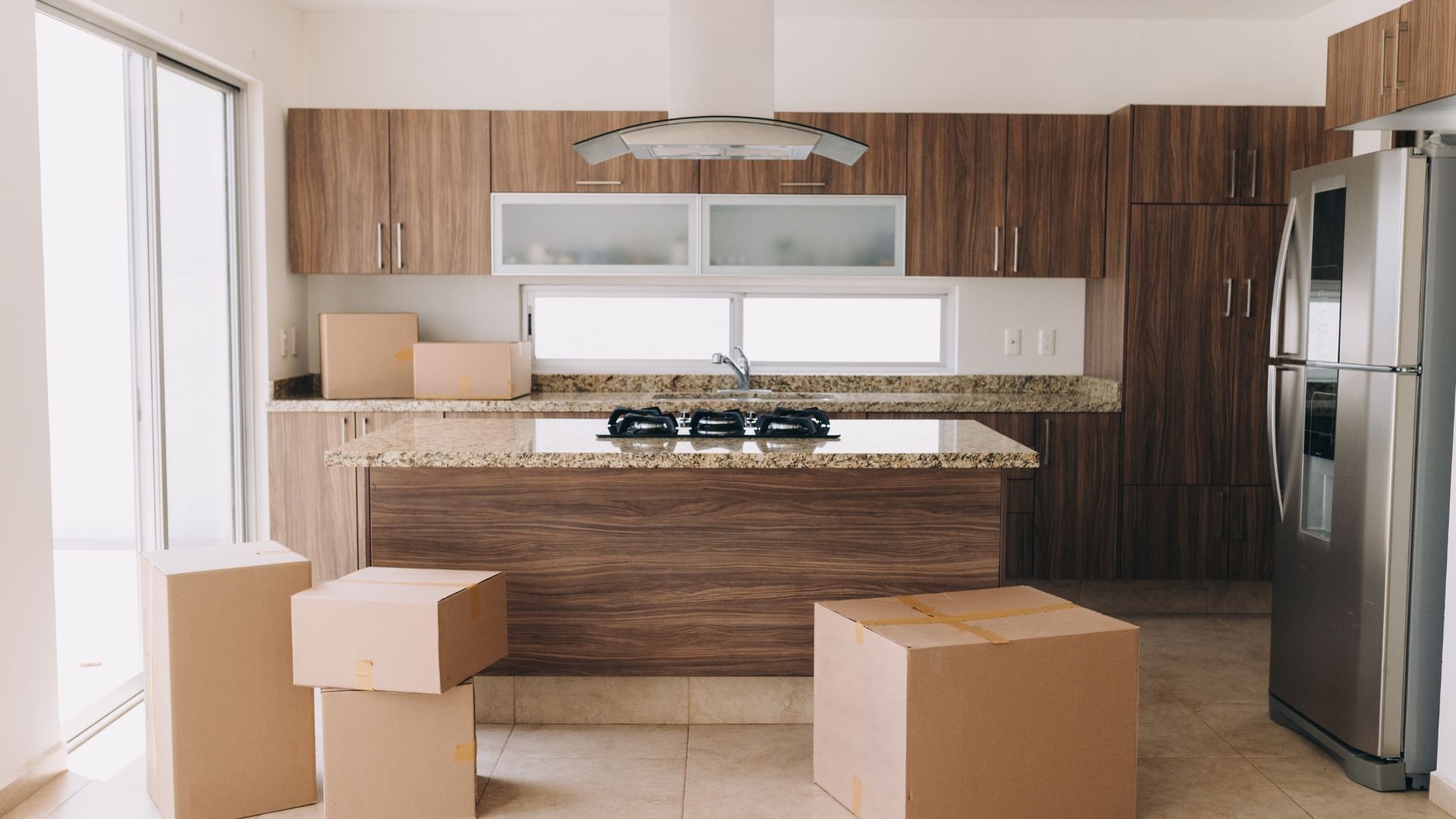 Modern kitchen with cardboard moving boxes and wooden cabinets